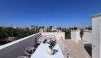 Terraza luminosa en la azotea con muebles blancos, zona lounge y vistas al mar de una casa de nueva construcción exclusiva en Puig de Ros.