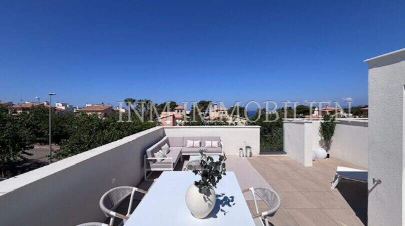 Terraza luminosa en la azotea con muebles blancos, zona lounge y vistas al mar de una casa de nueva construcción exclusiva en Puig de Ros.
