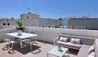 Terraza en la azotea soleada con muebles de exterior blancos, zona lounge y mesa de comedor, casa de nueva construcción en Puig de Ros, Mallorca.