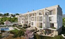 Vista exterior de moderno complejo residencial de nueva construcción en Palmanova con piscina, terrazas y exuberante vegetación, cerca de la playa.