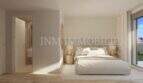 Bright bedroom of a new apartment in Palmanova with double bed, wooden floor and access to the terrace.