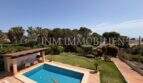 Gepflegter Außenbereich mit Pool, grünem Garten und Palmen des Chalets in Vallgornera, Cala Pi