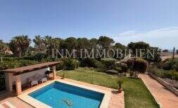 Área exterior bien mantenida con piscina, jardín verde y palmeras del chalet en Vallgornera, Cala Pi