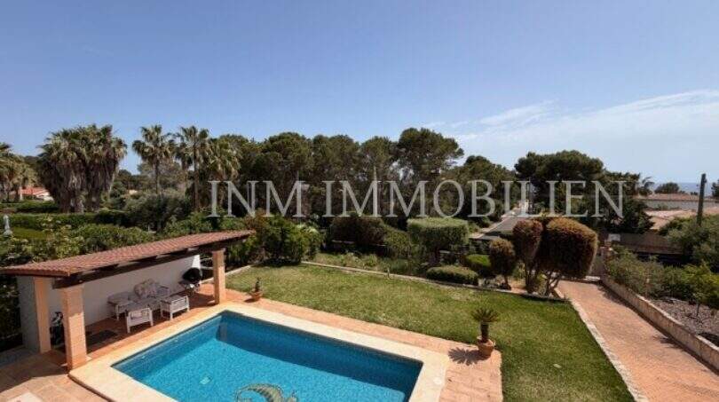 Gepflegter Außenbereich mit Pool, grünem Garten und Palmen des Chalets in Vallgornera, Cala Pi