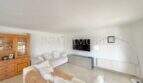 Helles Wohnzimmer des Chalets in Vallgornera mit weißen Sofas, TV-Bereich und Holzschrank, Fliesen