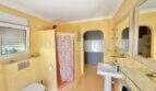 Helles Badezimmer mit gelbem Wandputz, Dusche mit Vorhang, Wandtoilette und Waschtisch im Chalet Vallgornera