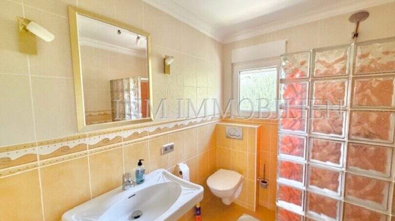 Helles Badezimmer mit Waschbecken, WC, Glasbausteindusche und gelblichen Fliesen im Chalet Vallgornera
