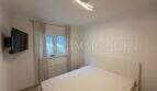 Helles Schlafzimmer mit Doppelbett, Wandmontiertem TV und Fenster im Chalet in Vallgornera, Cala Pi