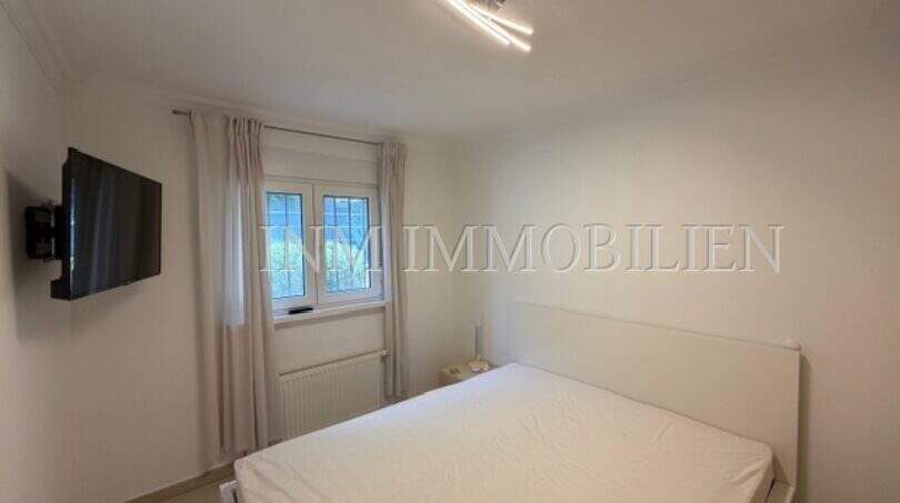 Helles Schlafzimmer mit Doppelbett, Wandmontiertem TV und Fenster im Chalet in Vallgornera, Cala Pi