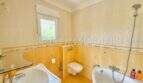 Helles Badezimmer mit Badewanne, WC und Waschbecken in gelbem Fliesendekor im Chalet Vallgornera
