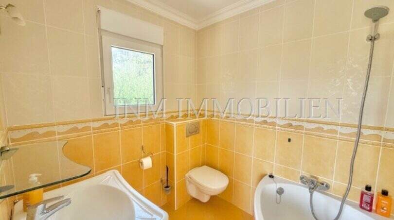 Helles Badezimmer mit Badewanne, WC und Waschbecken in gelbem Fliesendekor im Chalet Vallgornera