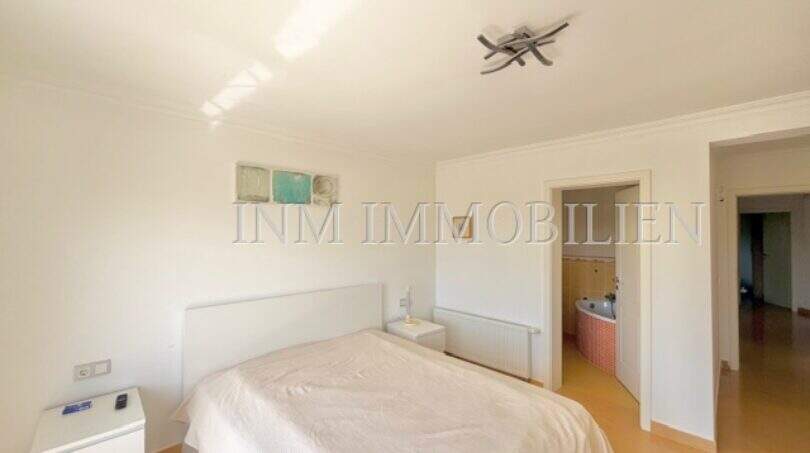 Helles Schlafzimmer mit Doppelbett, weißen Möbeln und direktem Zugang zum Bad im Chalet Vallgornera
