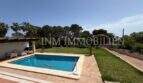 Gepflegter Außenbereich des Chalets in Cala Pi mit rechteckigem Pool, Terrasse und grünem Garten mit Palmen.