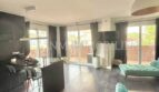 Bright living room with turquoise sofa, dark wooden floor and terrace access in sea view apartment Palma