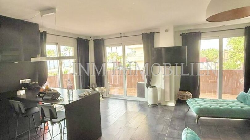 Bright living room with turquoise sofa, dark wooden floor and terrace access in sea view apartment Palma