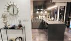 Modern living kitchen area with dark kitchen island, bar stools, designer mirror and stone tile floor in sea view apartment Palma