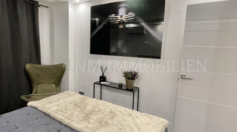 Modern bedroom of the sea view apartment in Las Maravillas with double bed, TV wall art and elegant armchair.