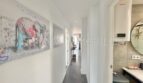 Bright hallway of the sea view apartment in Las Maravillas with elephant artwork, dark wood floor and modern bathroom.