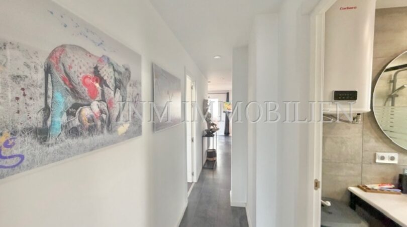 Bright hallway of the sea view apartment in Las Maravillas with elephant artwork, dark wood floor and modern bathroom.