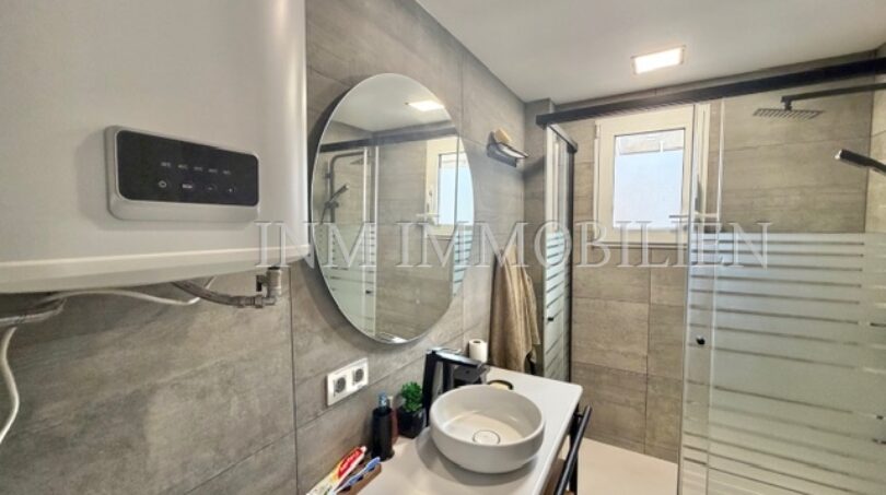 Modern bathroom of the sea view apartment in Las Maravillas with shower, sink and round mirror.