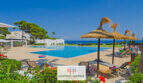 Gemeinschaftspool mit Meerblick, Sonnenliegen und Strohdächern in Apartmentanlage Cala d'Or