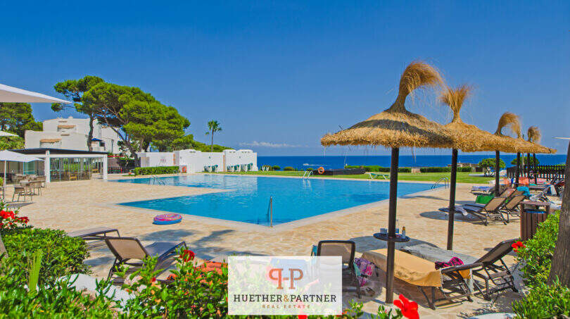 Gemeinschaftspool mit Meerblick, Sonnenliegen und Strohdächern in Apartmentanlage Cala d'Or