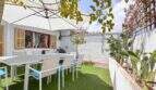 Sonnige Terrasse mit weißen Gartenmöbeln, Sonnenschirm und Kakteen in Felanitx