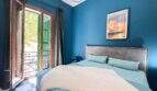 Schlafzimmer mit blauer Wand, Doppelbett, Balkon mit grünen Fensterläden und Mallorca-Poster in Felanitx