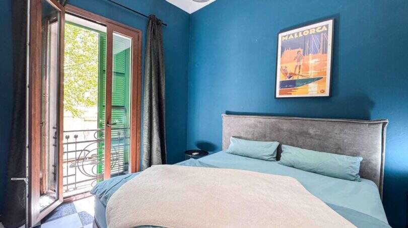 Schlafzimmer mit blauer Wand, Doppelbett, Balkon mit grünen Fensterläden und Mallorca-Poster in Felanitx