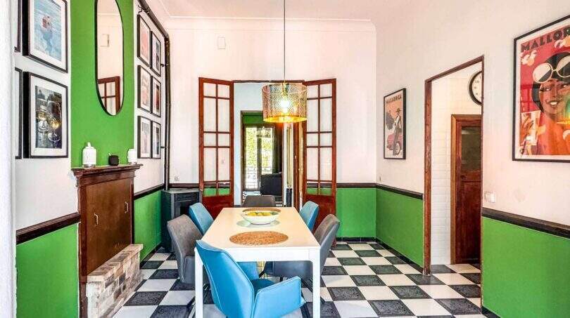 Esszimmer mit Schachbrettboden, grünen Wänden, weißem Tisch, blauen Stühlen und Mallorca-Postern in Felanitx