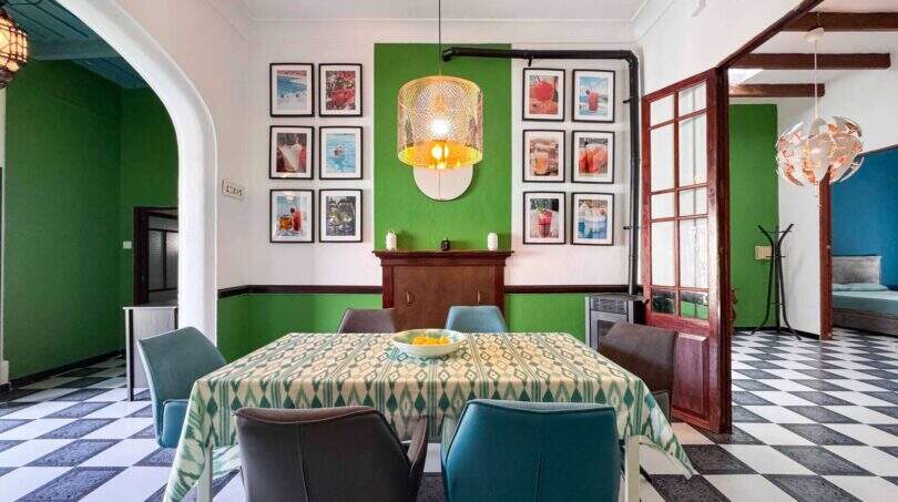 Esszimmer mit grünen Wänden, Schachbrettboden, gedecktem Tisch und Kunstgalerie in Felanitx
