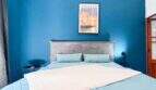 Schlafzimmer mit Doppelbett, blauer Akzentwand und Mallorca-Poster in stilvoller Wohnung in Felanitx