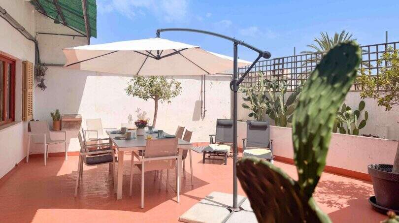 Sonnige Dachterrasse mit Esstisch, Sonnenschirm und Kakteen in Felanitx-Wohnung