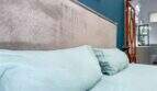 Schlafzimmer mit hellblauer Bettwäsche, gepolstertem Kopfteil und Blick ins angrenzende Bad in Felanitx