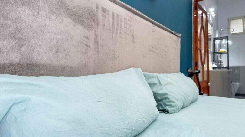 Schlafzimmer mit hellblauer Bettwäsche, gepolstertem Kopfteil und Blick ins angrenzende Bad in Felanitx