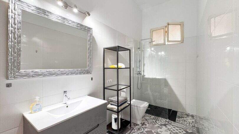 Helles Badezimmer mit Glasdusche, Waschtisch, Wandspiegel und Zementfliesen in Wohnung Felanitx