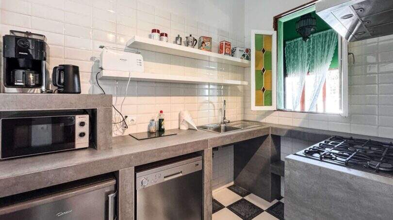 Moderne Küche mit Gasherd, Geschirrspüler, Mikrowelle und buntem Buntglasfenster in Wohnung Felanitx