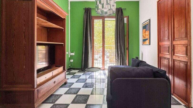 Wohnzimmer mit grünen Wänden, Schachbrettboden, TV-Möbel und Balkonzugang in Felanitx
