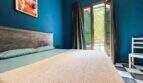 Schlafzimmer mit Doppelbett, blauer Wand, Balkon mit grünen Fensterläden und Schachbrettboden in Felanitx