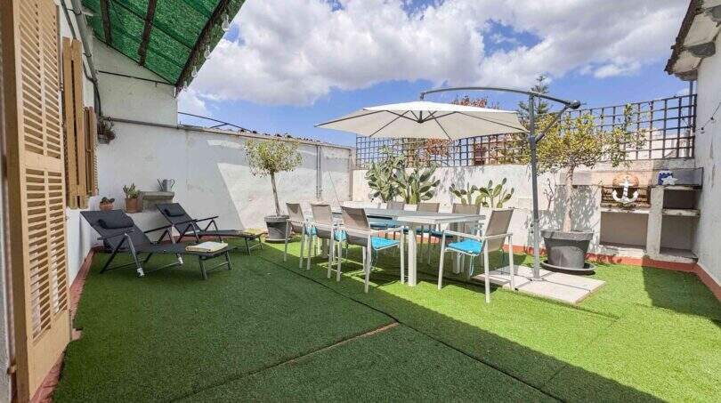 Sonnige Dachterrasse mit Kunstrasen, Esstisch, Loungestühlen und Sonnenschirm in Felanitx