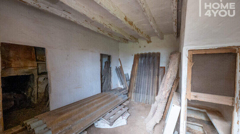 Renovierungsbedürftiger Innenraum der Finca mit Holzbalkendecke, Natursteinwänden und Baumaterialien
