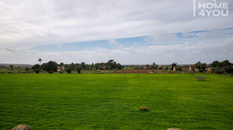 Weitläufige grüne Wiese der Natursteinfinca bei Campos mit Blick auf Landschaft und historische Gebäude