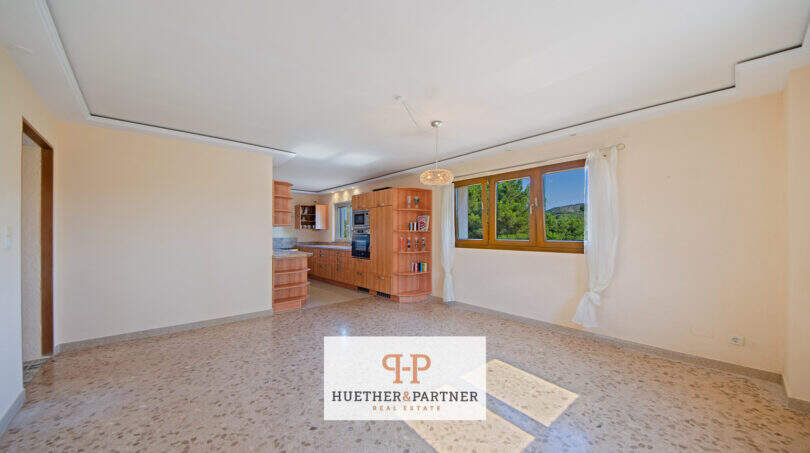 Helles Wohn-Esszimmer der Finca Son Macià mit offener Küche, Terrazzoböden und Ausblick ins Grüne.
