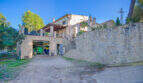Finca Son Macià: Steingebäude mit Garage, John Deere Traktor, Balkon und großer Natursteinmauer im Außenbereich.