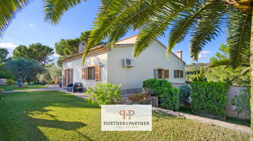 Außenansicht der Finca Son Macià: mediterranes Landhaus mit Palmengarten, Holzläden und üppigem Grün