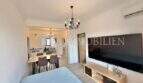 Luminoso salón con gran televisor, mesa de comedor y lámpara de araña en apartamento renovado en Palma