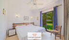 Helles Schlafzimmer mit Doppelbett, Deckenventilator und Terrassenzugang zum grünen Garten in Cala d'Or.