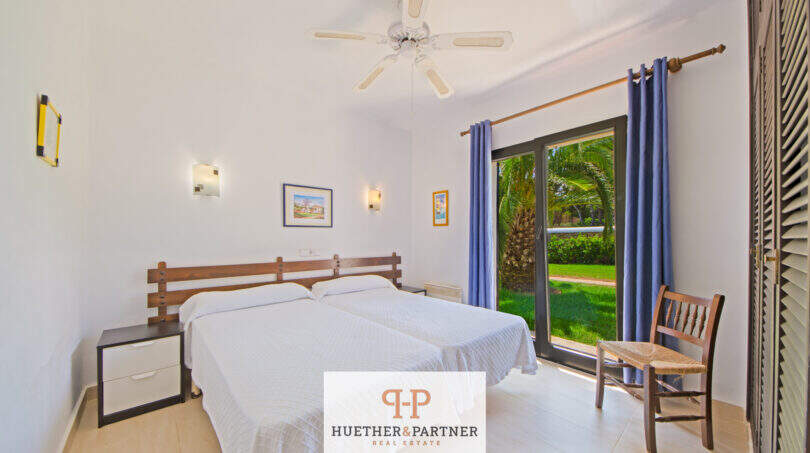 Helles Schlafzimmer mit Doppelbett, Deckenventilator und Terrassenzugang zum grünen Garten in Cala d'Or.