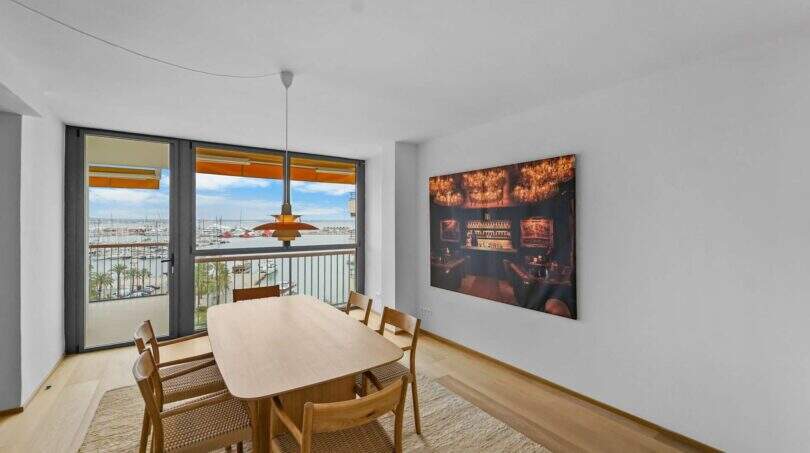 Elegantes Esszimmer der Luxuswohnung am Paseo Marítimo mit Hafenblick, Holztisch und moderner Hängeleuchte.