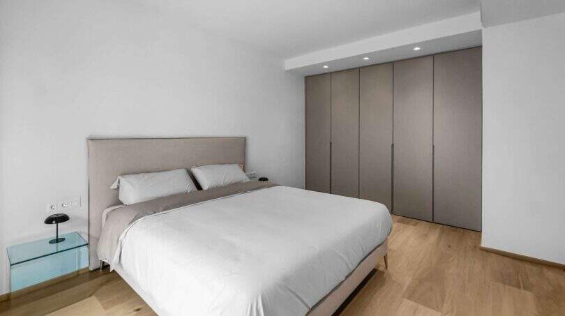 Helles Schlafzimmer der Luxuswohnung am Paseo Marítimo mit Doppelbett, Einbauschrank und Holzboden.